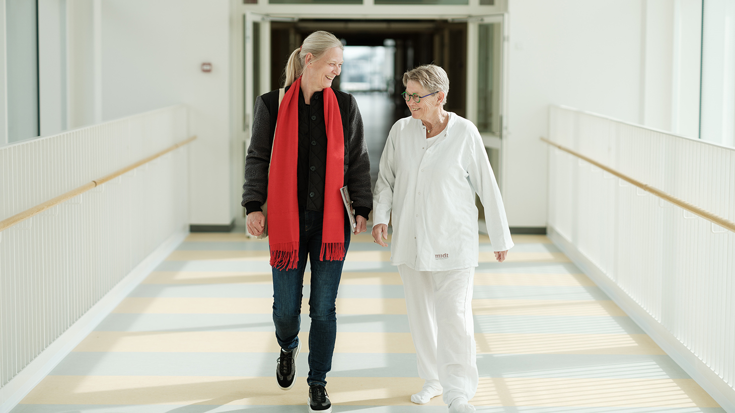 Patient og pårørende går en tur på hospitalsgangen.lsseng.