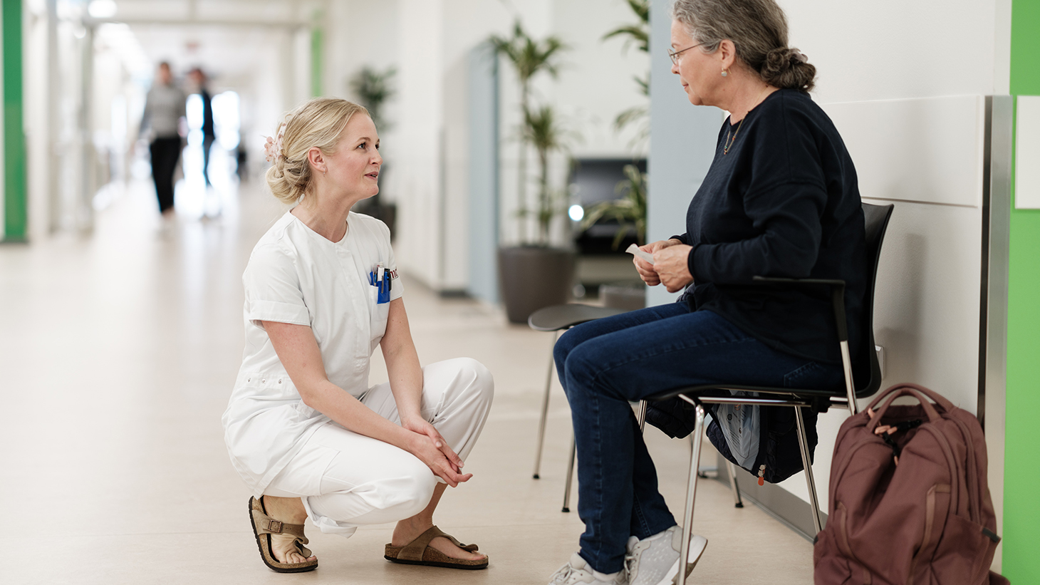 Sygeplejerske taler med patient i venteområde
