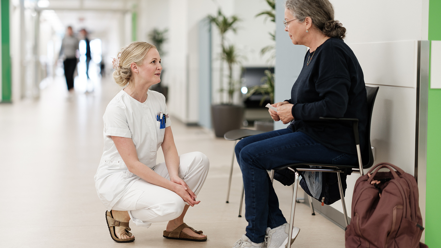 Pårørende taler med sygeplejerske på hospitalsgangen.