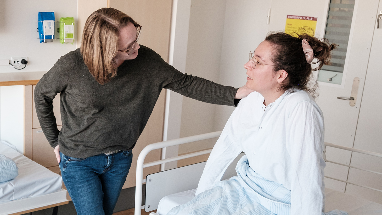 Pårørende holder en hånd på patients skulder.