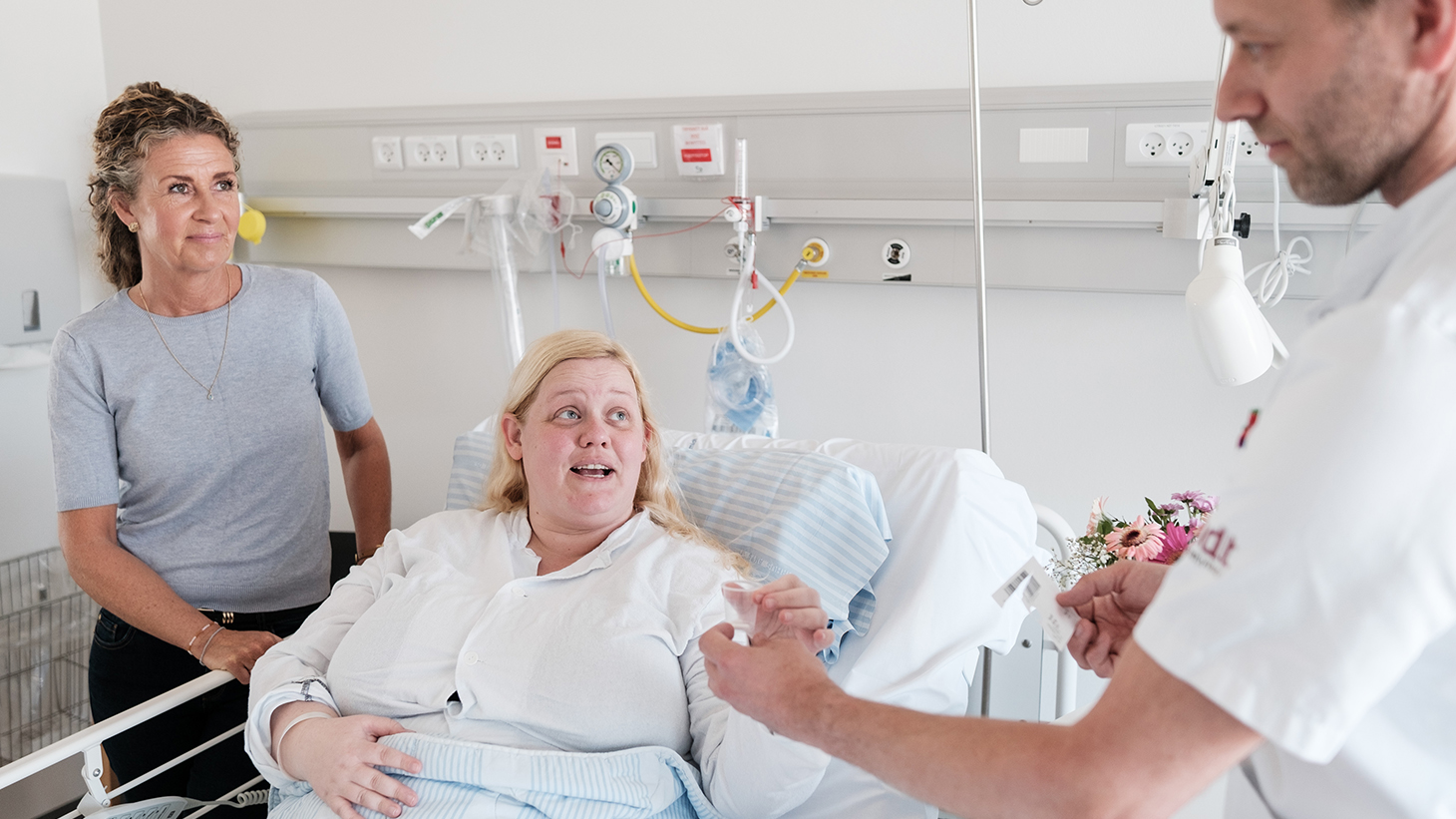 Patient og pårørende taler med sygeplejerske ved sengekanten