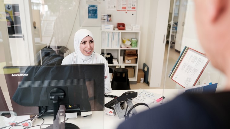 Bioanalytiker tager imod patient ved skranken.